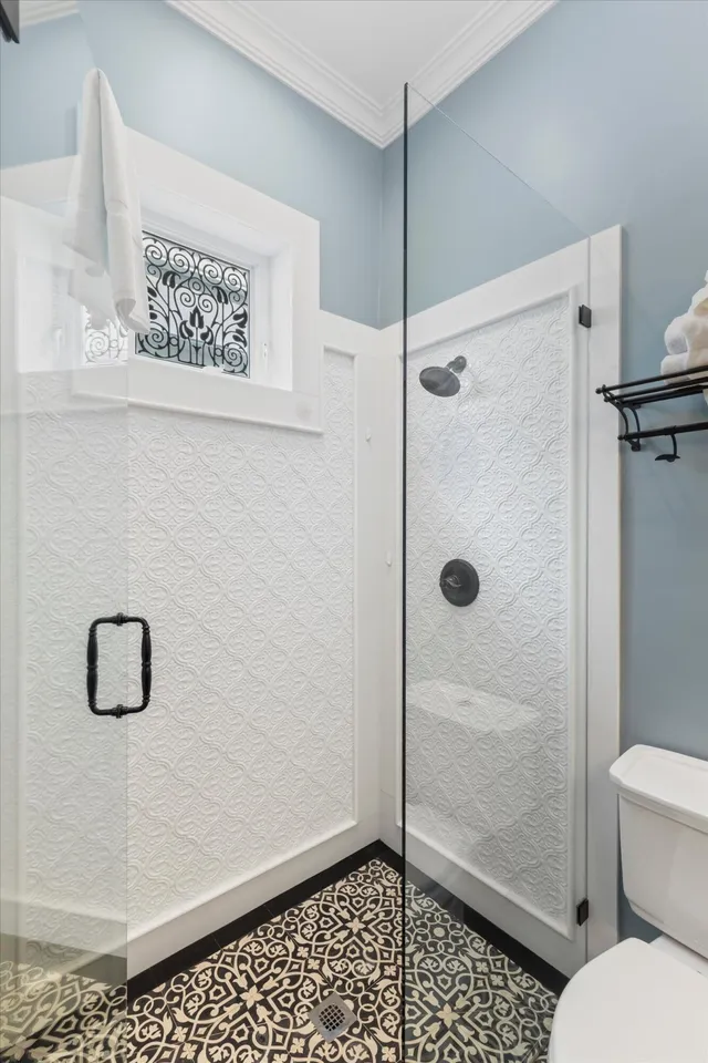 Bathroom with glass walk-in shower, patterned tile floor and blue walls