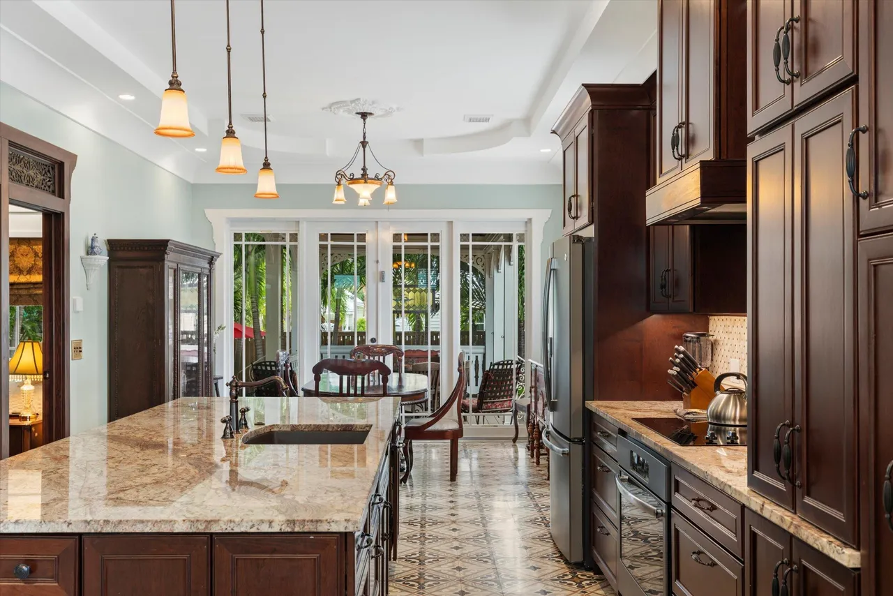 Gourmet kitchen with granite island, dark wood cabinetry and pendant lighting