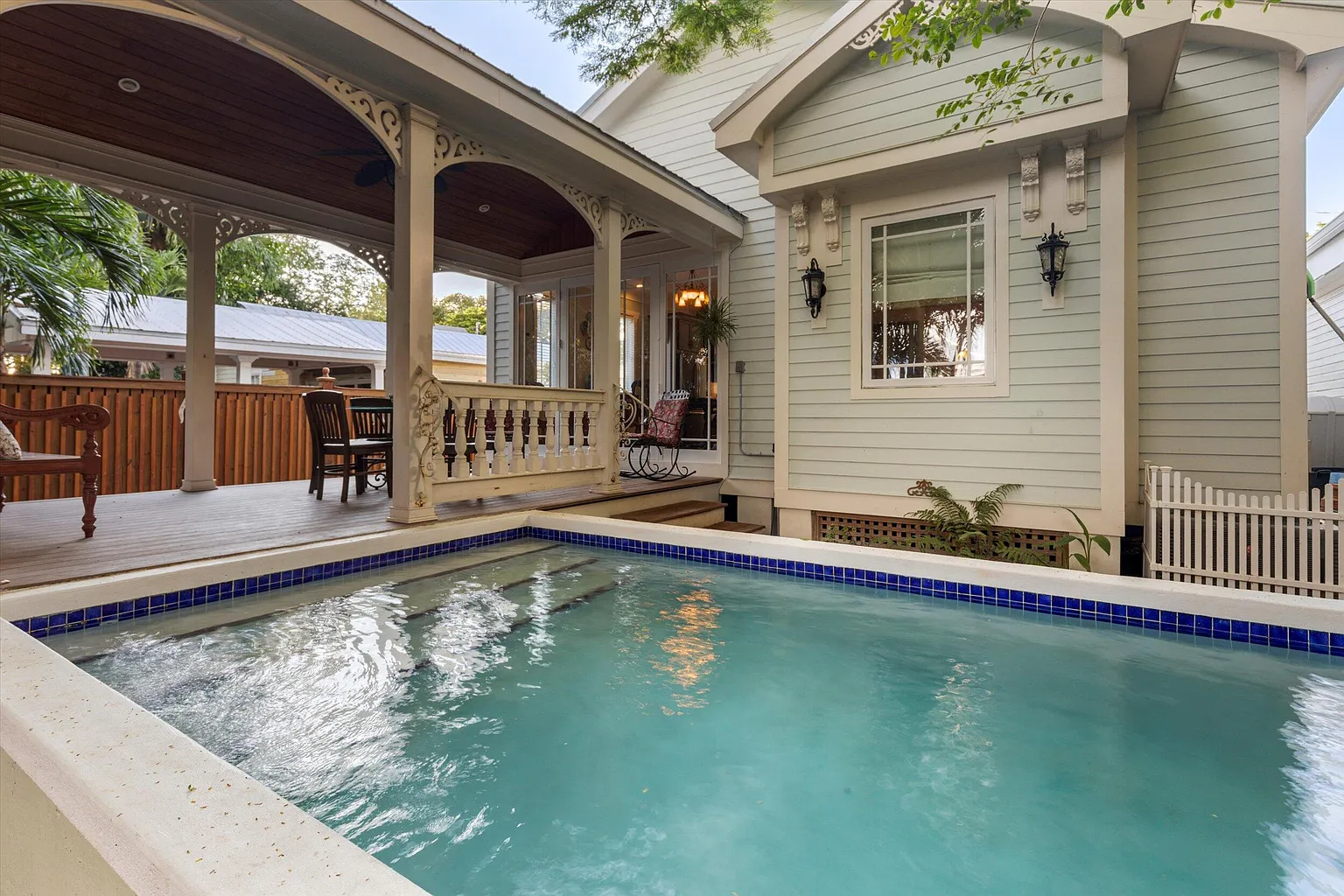 Private heated pool with blue tile edging beside the covered porch